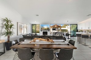 Uma sala de jantar moderna com uma mesa grande, cadeiras e um objeto decorativo no centro.