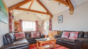 A cozy living room with two leather sofas, a wooden coffee table, and a red patterned rug.
