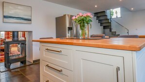 A modern kitchen with a wooden countertop, white cabinets, and a vase of pink flowers.
