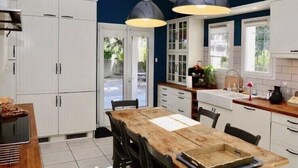 A kitchen with white cabinets, a wooden dining table, and pendant lighting. - Spacious, bright villa. Charm, comfort and calm. Heated swimming pool. (Argilliers)