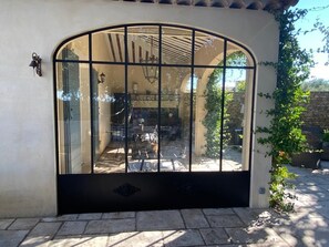 Un espace patio avec une porte vitrée donnant sur une cuisine, des murs en pierre et un luminaire suspendu.