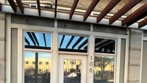 A building facade with a large entrance door, a visible number '106', and a metal roof structure. - 2 Bed, 2 Bath Apartment at Cannery Square (Sun Prairie)