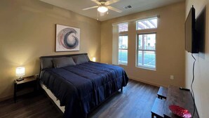 A bedroom with a bed, a ceiling fan, a window, and a TV mounted on the wall. - 2 Bed, 2 Bath Apartment at Cannery Square (Sun Prairie)