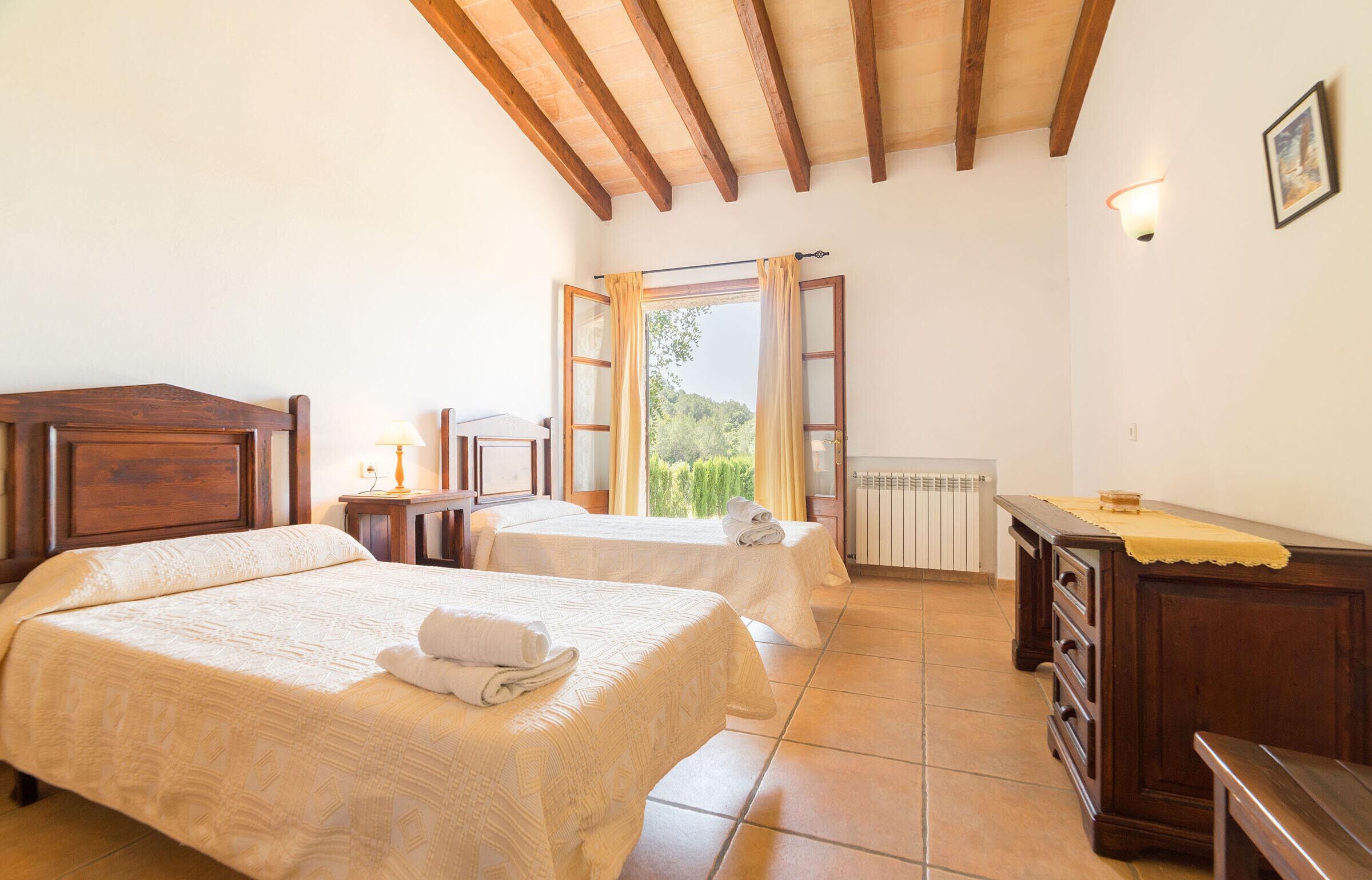 Une chambre avec deux lits, un plafond en bois, une fenêtre avec des rideaux et un radiateur.