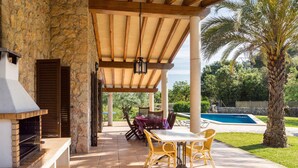 An outdoor patio with a stone wall, a wooden pergola, a pool, and outdoor furniture. - CADELL PETIT. Charming house a short drive away from Pollensa (Pollensa / Pollença)
