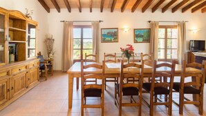 A dining area with wooden tables and chairs, a wooden cabinet, and a television. - CADELL PETIT. Charming house a short drive away from Pollensa (Pollensa / Pollença)