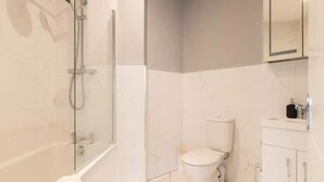 Un baño moderno con ducha envuelta en vidrio, inodoro y lavabo con espejo.