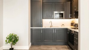 Una cocina moderna con armarios oscuros, electrodomésticos de acero inoxidable y una planta en maceta.