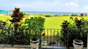 Uma varanda com vista para uma área gramada e o oceano.