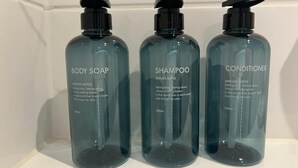 Three bottles of body soap, shampoo, and conditioner on a white shelf. - Stylish Central Studio Apartment Modern Luxury (Brighton)