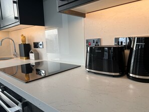 Une cuisine moderne dotée d’un plan de travail en marbre noir et blanc, d’un évier en acier inoxydable et d’une machine à café.