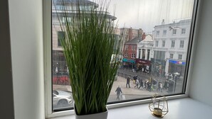 A window with a potted plant and a small table with a candle holder. - Stylish Central Studio Apartment Modern Luxury (Brighton)