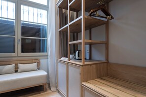 A room with a wooden bench, a cushioned bench, and a built-in shelf with a kettle and a mug. - Malabar by Petit Palace Anteriormente Icon Malabar (Málaga)
