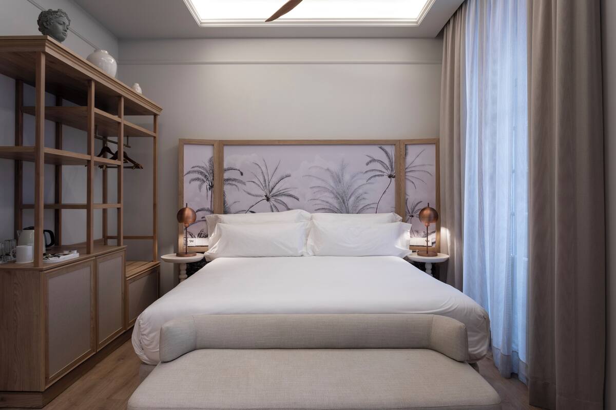 A modern bedroom with a large bed, a wooden wardrobe, and a ceiling light.