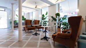 Een ruime lobby met moderne meubels, grote ramen en potplanten.