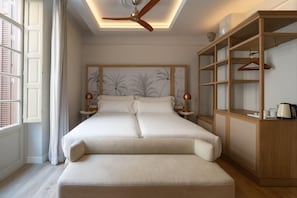 Un dormitorio con una cama grande, un ventilador de techo, un armario de madera y una ventana con contraventanas.