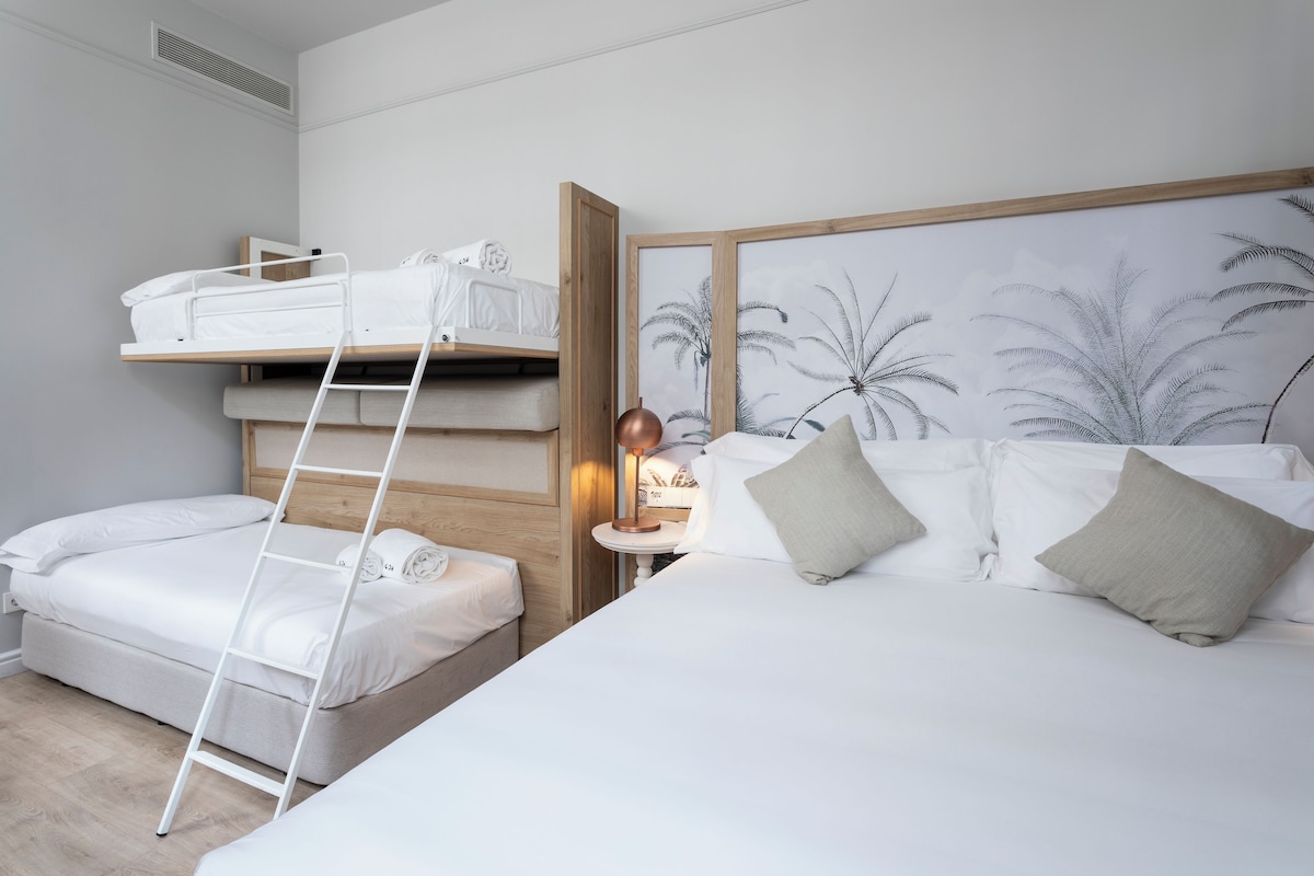 A bedroom with a bunk bed, a single bed, and a nightstand with a lamp.
