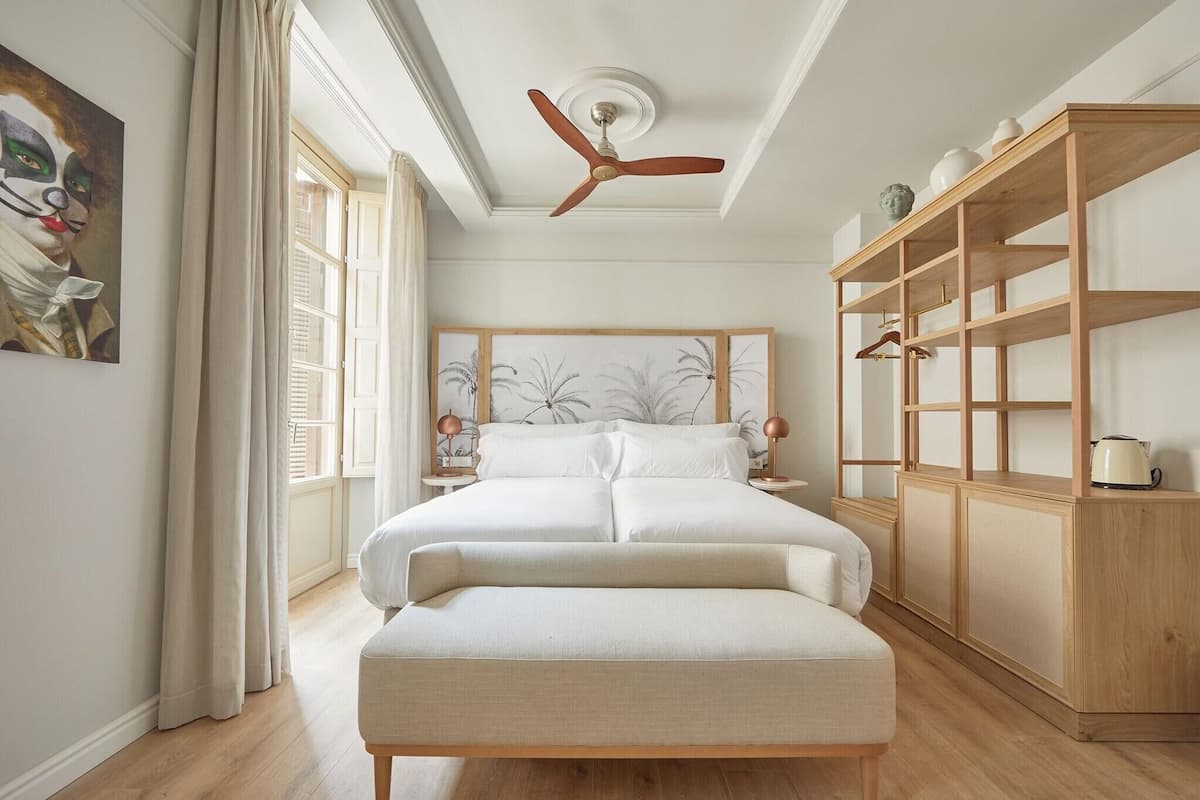 Ein Schlafzimmer mit einem Bett, einem Holzschrank, einem Deckenventilator und einem Gemälde an der Wand.
