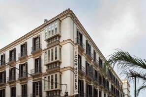 A multi-story building with a sign reading "ICON HOTELS" on the corner. - Malabar by Petit Palace Anteriormente Icon Malabar (Málaga)
