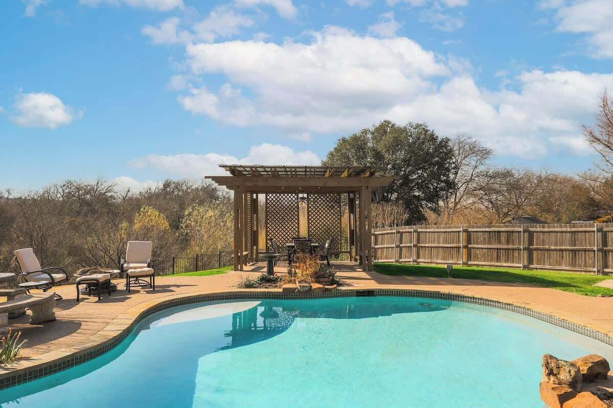 Un jardin avec une piscine, des meubles de patio et une pergola.