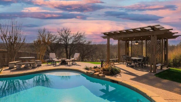 A swimming pool with a pergola and outdoor seating area. - Elite 4BR/2B Home with Hot Tub, Pool, and BBQ (Haltom City)