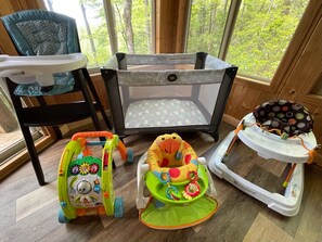 Enjoy a serene view of the wooded area from the large window, perfect for a family stay with a playpen, high chair, and baby walker.