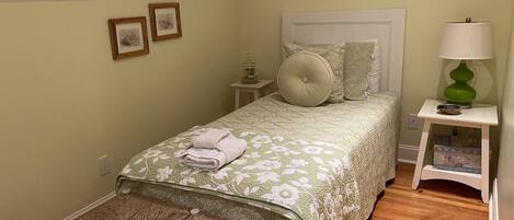 A neatly arranged bedroom with a bed, a bedside table, a lamp, and a bench.
