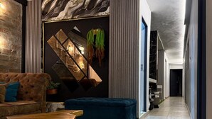 A modern living room with a sofa, a blue ottoman, a wooden coffee table, and a decorative wall with a geometric pattern and a hanging plant. - house with jacuzzi near lleras park  (Medellin)