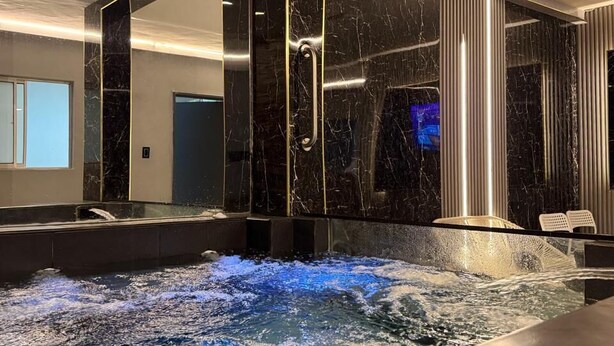 A modern spa area with a hot tub, marble walls, and a large mirror. - house with jacuzzi near lleras park  (Medellin)