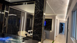 A modern bathroom with a black marble wall, a glass-enclosed hot tub, and a white chair. - house with jacuzzi near lleras park  (Medellin)