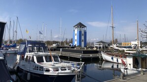 Een jachthaven met boten afgemeerd, een kleine toren en een houten steiger.