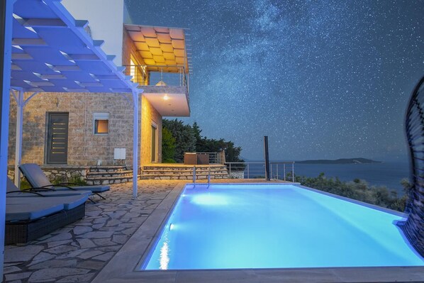 Un espace aménagé au bord de la piscine, offrant une vue dégagée sur la mer et sur les étoiles la nuit.