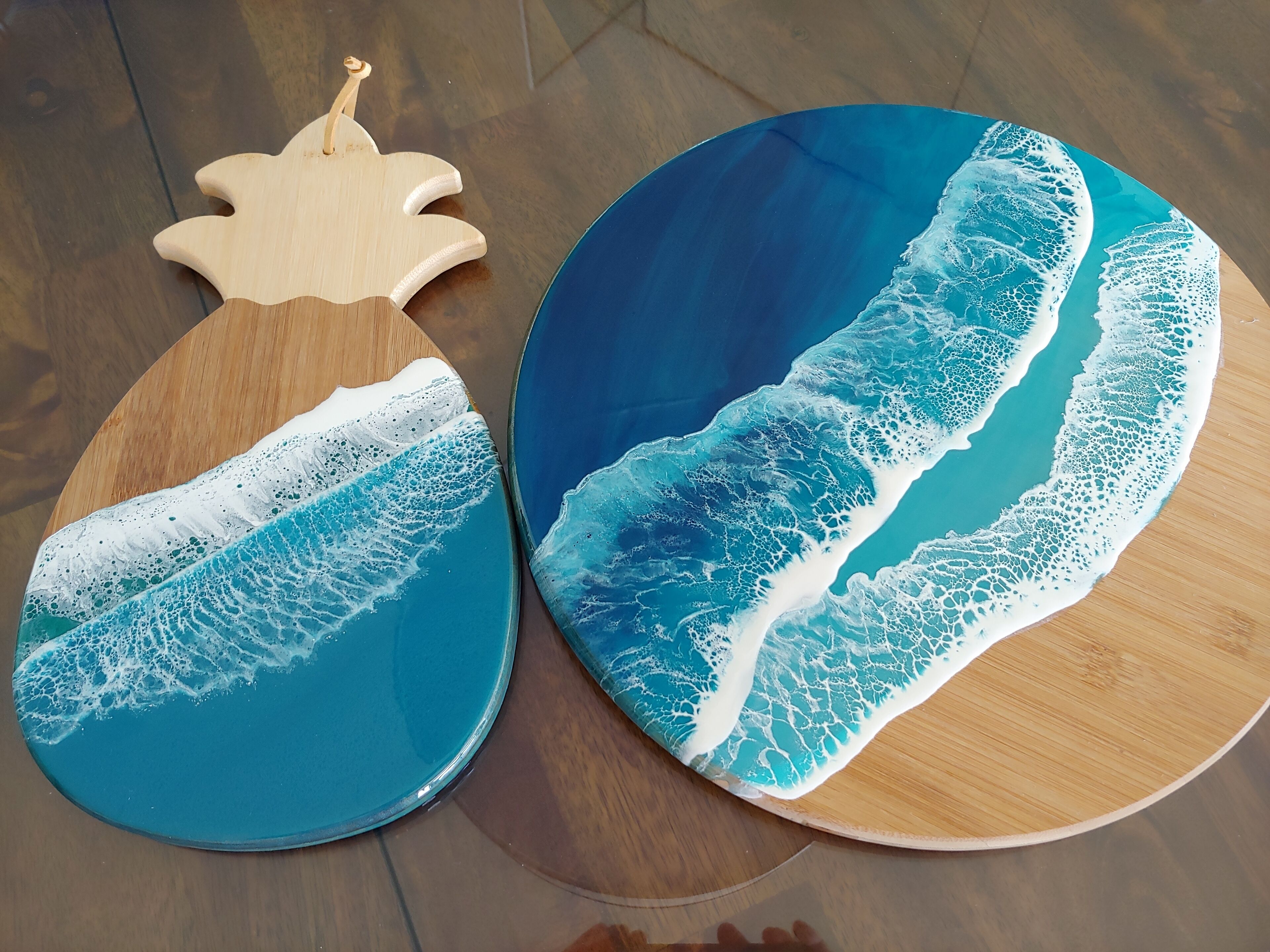 Deux sous-verres en bois ornés de motifs représentant des vagues.