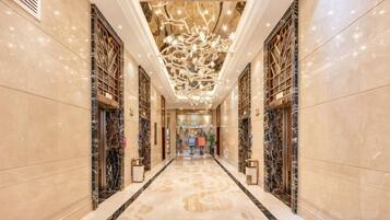 A long, narrow hallway with marble flooring and decorative ceiling lights.