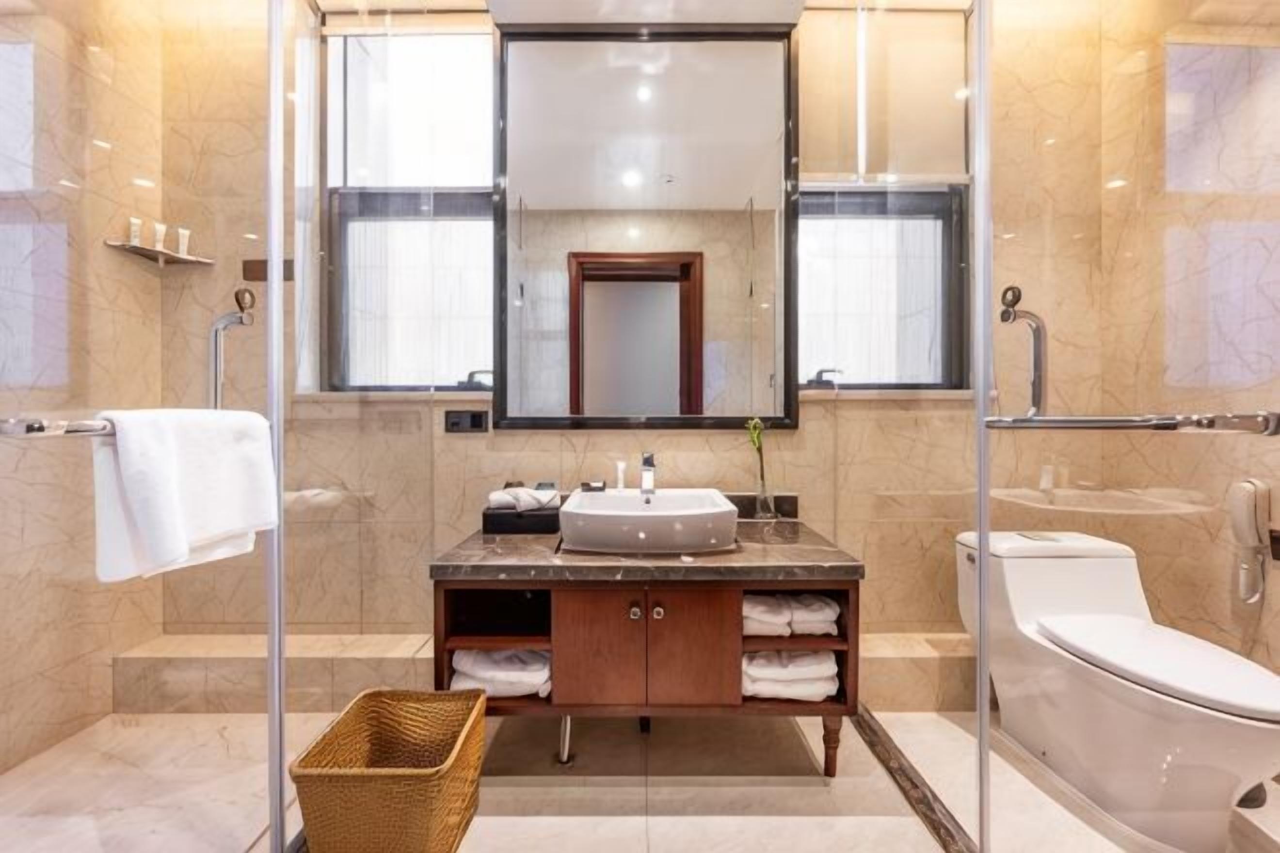Ein modernes Badezimmer mit Duschkabine aus Glas, einem Waschbecken mit Marmorplatte und einer Toilette.