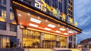 A hotel with a modern facade, a prominent entrance with a glass canopy, and a statue in front. - Taihe Hotel (Guyuan)