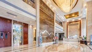 A spacious lobby with a high ceiling, a reception desk, and a large decorative wall. - Taihe Hotel (Guyuan)