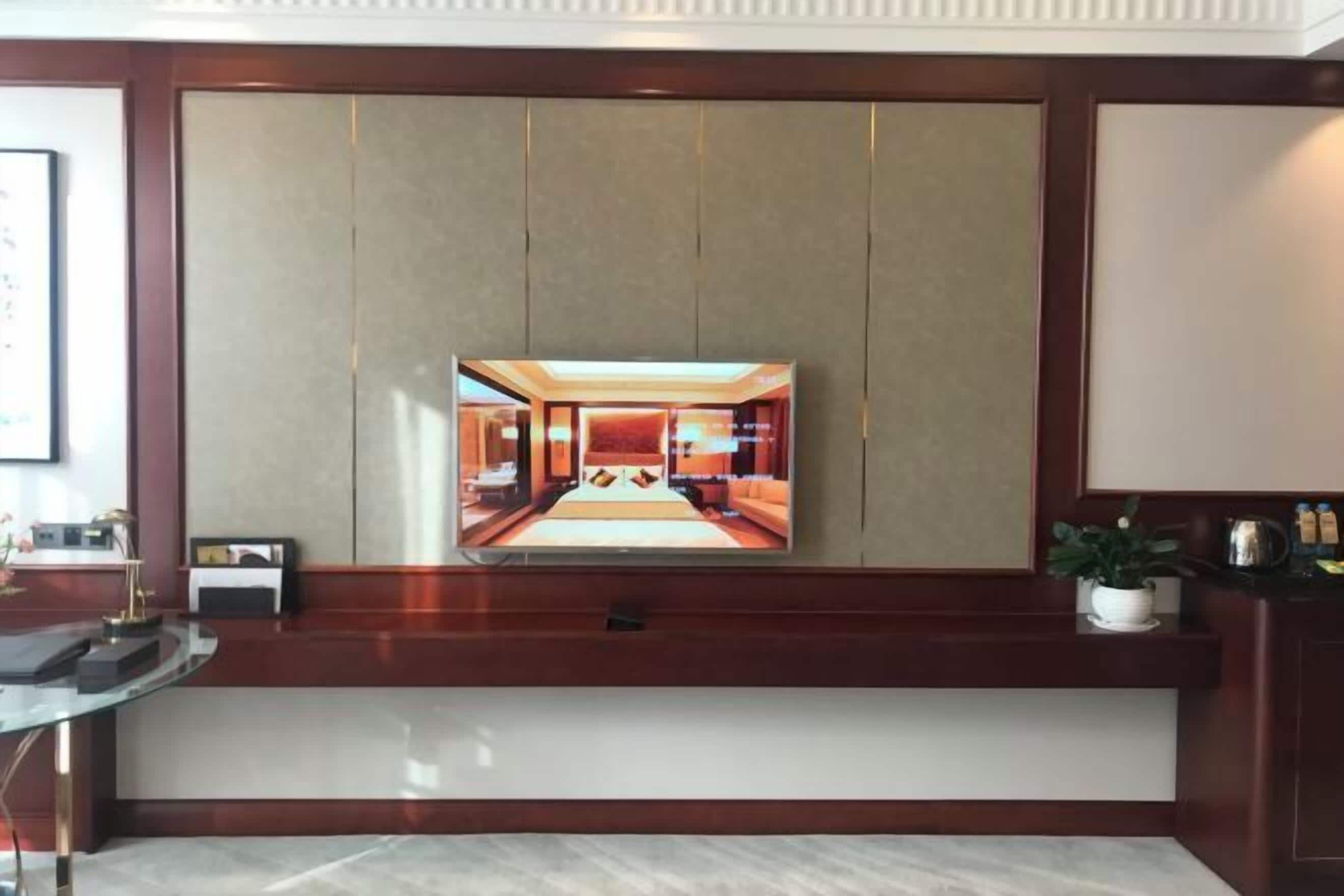 Un espace d’accueil moderne, doté d’un grand miroir qui reflète un intérieur bien éclairé, d’un comptoir de réception et d’une plante en pot.