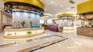 A hotel lobby with a central reception desk, a curved staircase, and a seating area. - Taihe Hotel (Guyuan)