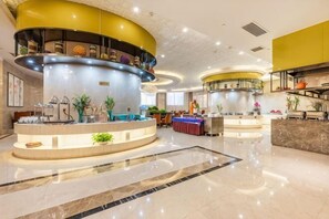 A hotel lobby with a central reception desk, a curved staircase, and a seating area. - Taihe Hotel (Guyuan)
