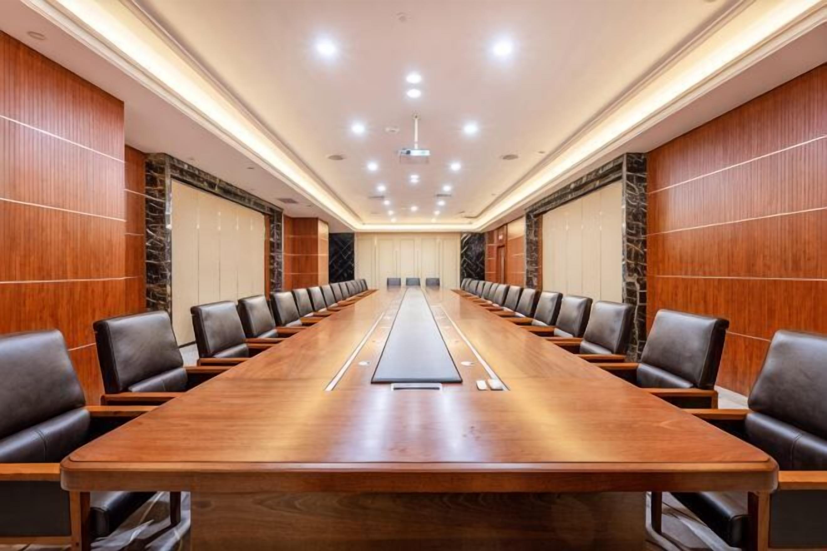 Un salón de conferencias con una mesa larga, varias sillas y una pantalla para proyector.
