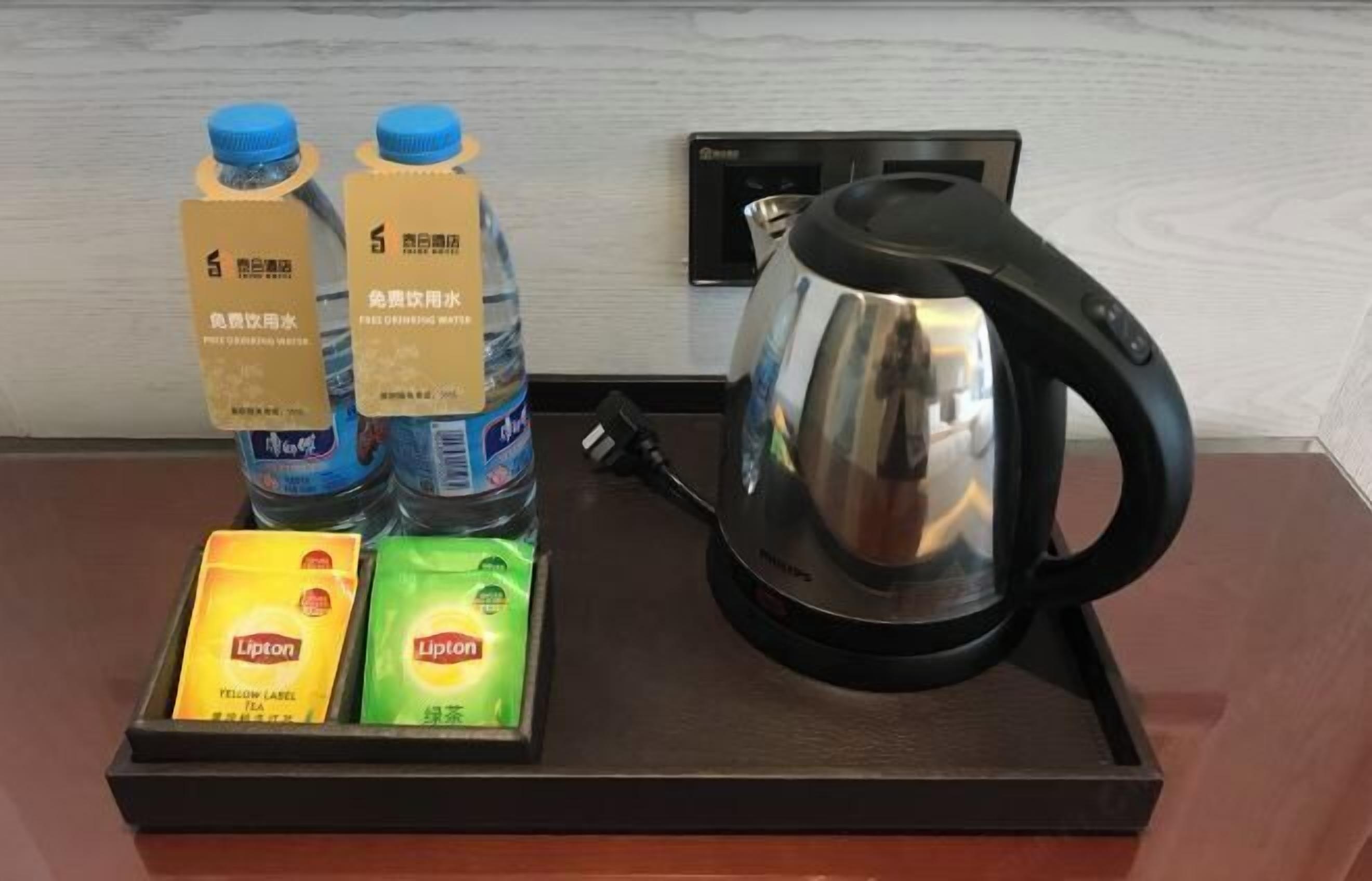 A hotel room's reception area with a tray containing bottled water, Lipton tea, and a kettle.