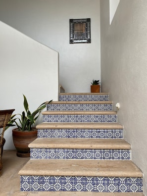 Eine Treppe mit blau gemusterten Fliesen, ein Blumentopf und ein gerahmtes Bild an der Wand.