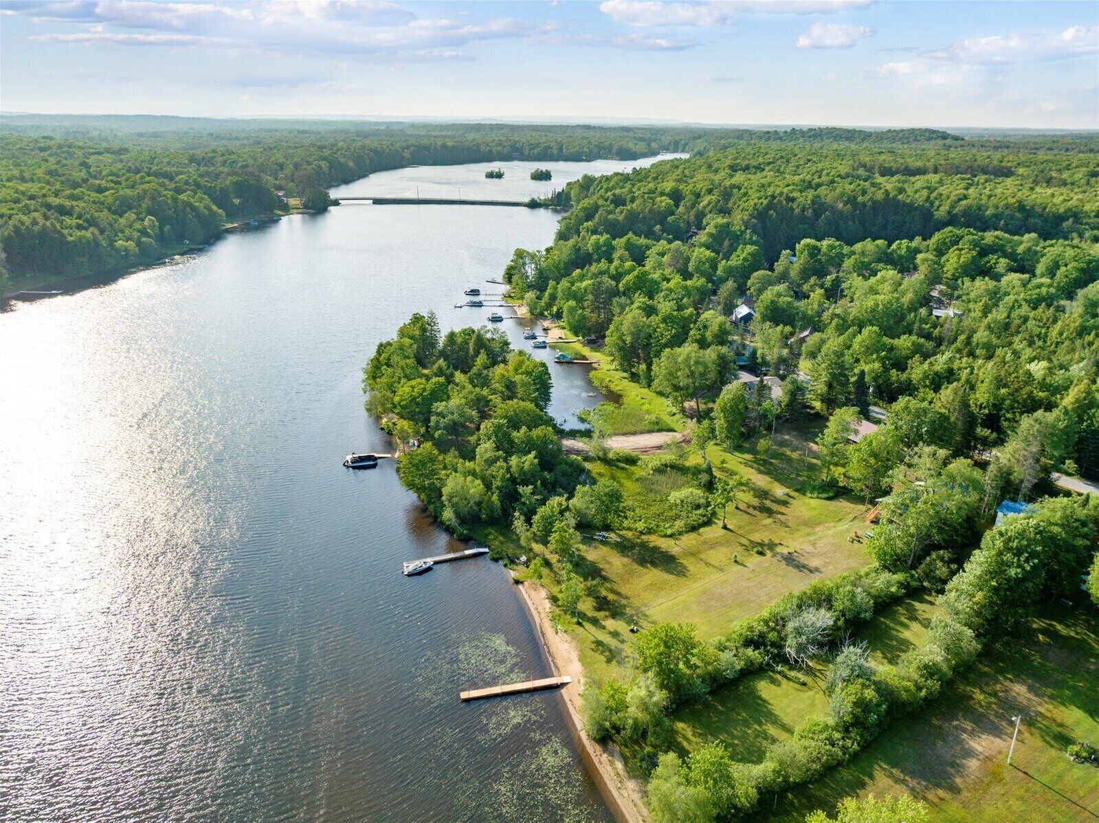Een pand aan de rivier met afgemeerde boten, omringd door dicht bos en een heldere lucht.