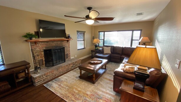A living room with a fireplace, a ceiling fan, a sofa, and a coffee table. - Watch Florida sunsets from the covered lakefront dock (Minneola)