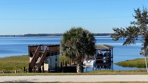 A wooden dock leading to a small building with a covered seating area and a boat docked nearby. - Watch Florida sunsets from the covered lakefront dock (Minneola)
