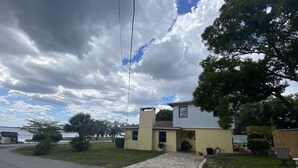 A two-story house with a front porch, a small front yard, and a view of a body of water. - Watch Florida sunsets from the covered lakefront dock (Minneola)