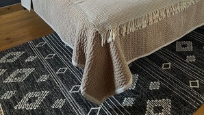 Ein Schlafzimmer mit einem großen Bett, einem dunklen Holz-Kopfteil, einem Fenster mit Aussicht und einem gemusterten Teppich.