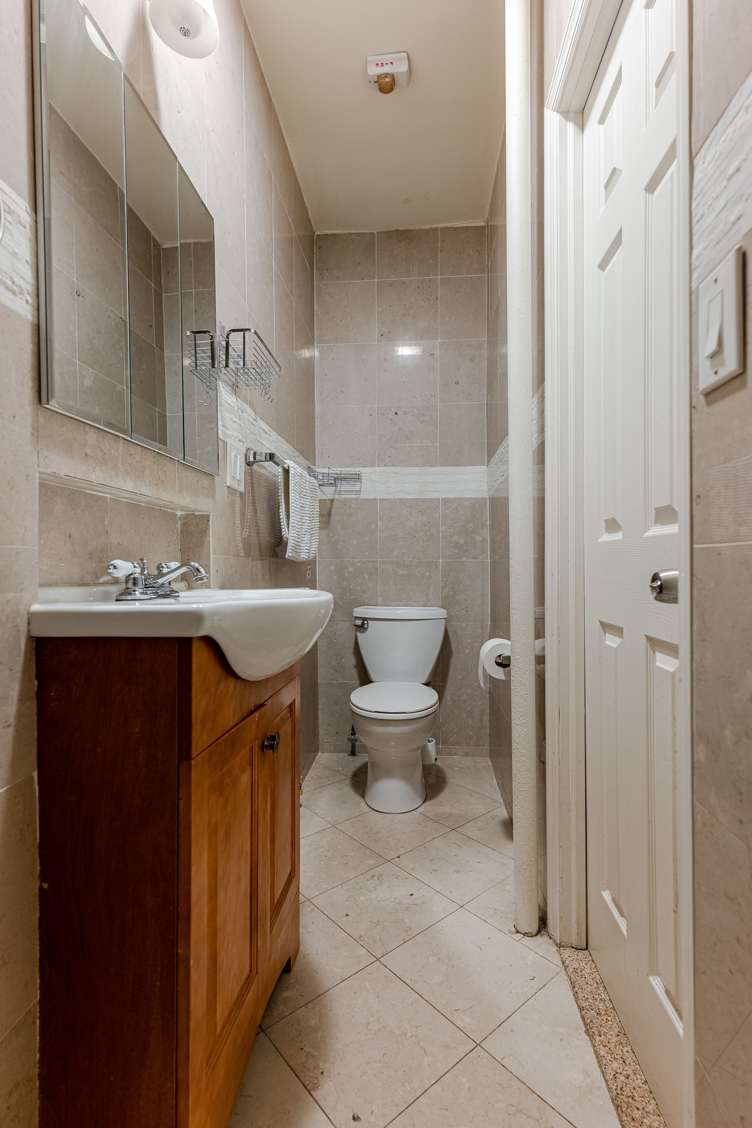 A bathroom with a wooden vanity, a toilet, and a shower area.