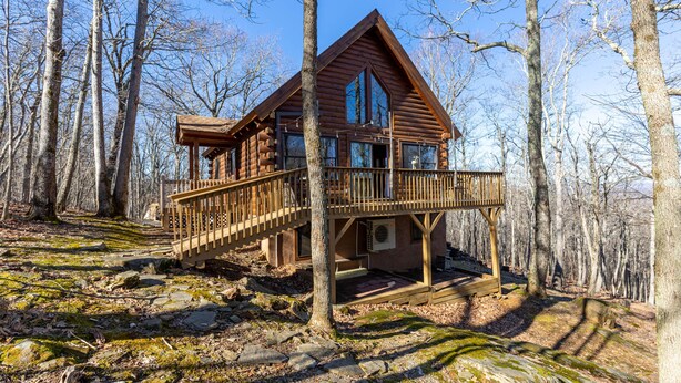 A wooden cabin with a balcony, surrounded by trees. - Adventure Creek - pet friendly, hot tub, creek on site, ping pong (Boone)